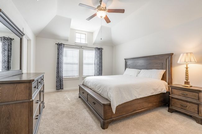Bedroom with baseboards, a ceiling fan, high vaulted ceiling, and light colored carpet | Image 15