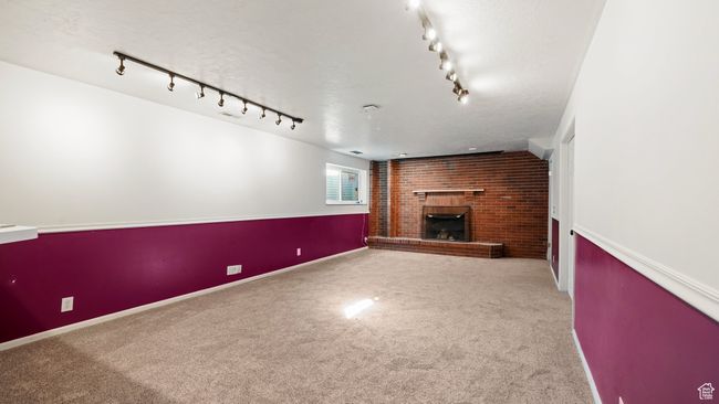 Unfurnished living room featuring carpet flooring, baseboards, a fireplace, and a textured ceiling | Image 17