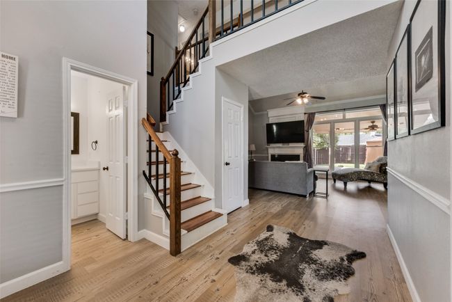 Staircase with wood finished floors, ceiling fan, a fireplace, and a towering ceiling | Image 4