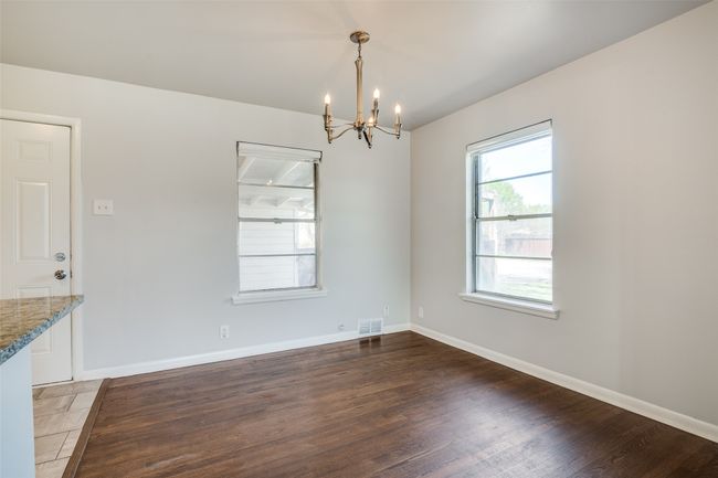Unfurnished dining area with a notable chandelier, baseboards, visible vents, and wood finished floors | Image 8