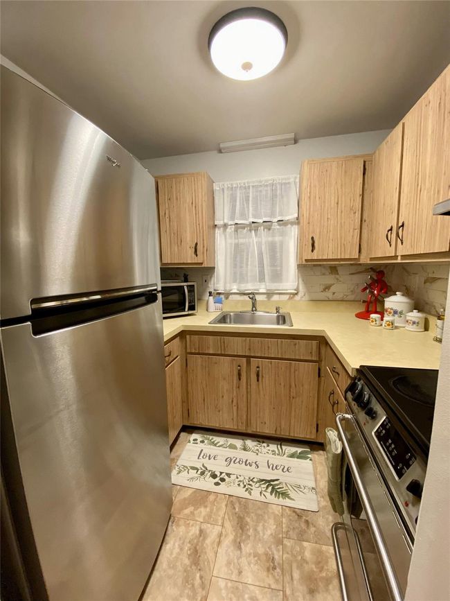 Kitchen with light brown cabinetry, appliances with stainless steel finishes, light countertops, and a sink | Image 36