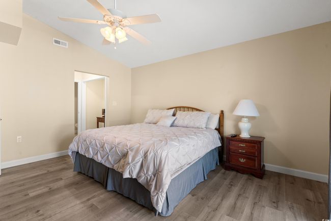 Bedroom with wood finished floors, vaulted ceiling, baseboards, and ceiling fan | Image 23