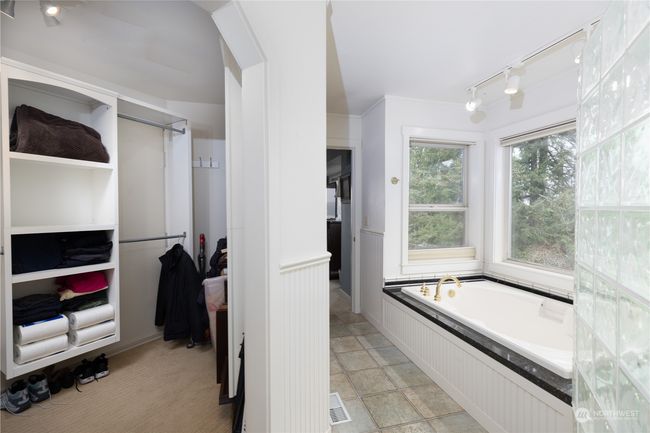 Primary bath with soaking tub, tile floors, and walk in custom closet | Image 32