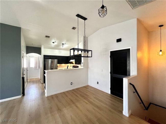 Kitchen featuring freestanding refrigerator, dark cabinetry, lofted ceiling, and light wood finished floors | Image 5
