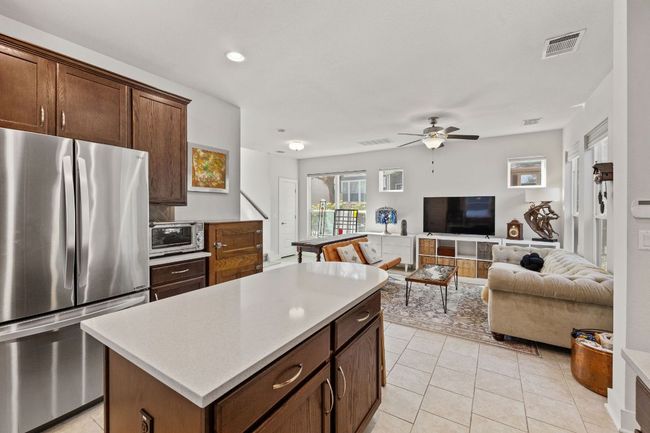 Kitchen featuring light countertops, ceiling fan, open floor plan, a center island, and freestanding refrigerator | Image 9