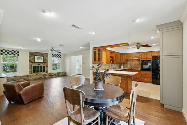 Dining area featuring ceiling fan, light wood-style flooring, a fireplace, ornamental molding, and recessed lighting | Image 15