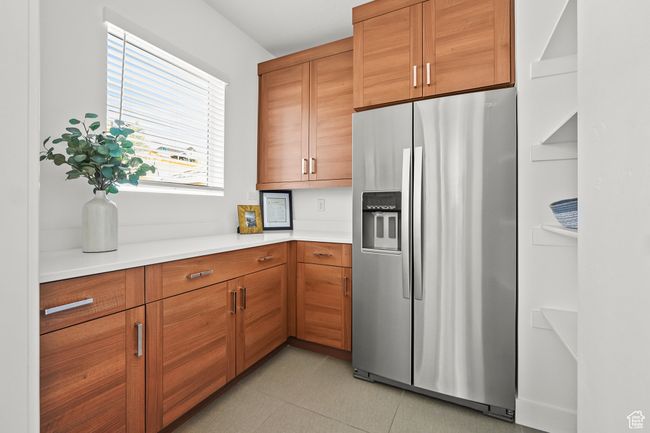 Kitchen featuring stainless steel fridge with ice dispenser, light countertops, brown cabinetry, and light tile patterned floors | Image 14
