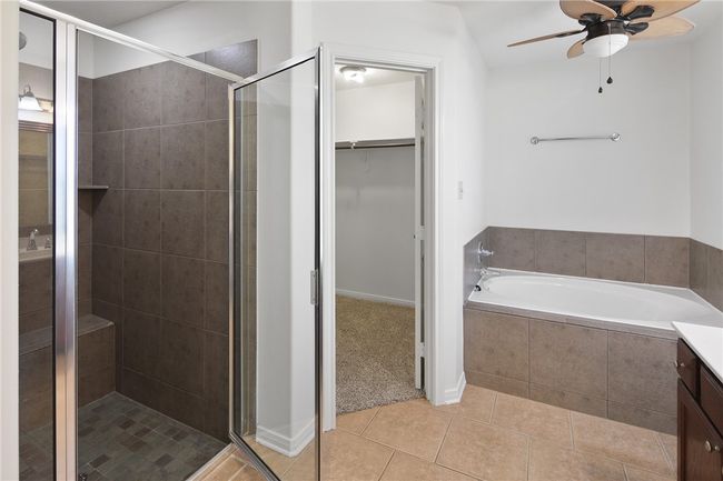 Full bathroom featuring tile patterned flooring, a shower stall, a walk in closet, a bath, and ceiling fan | Image 8