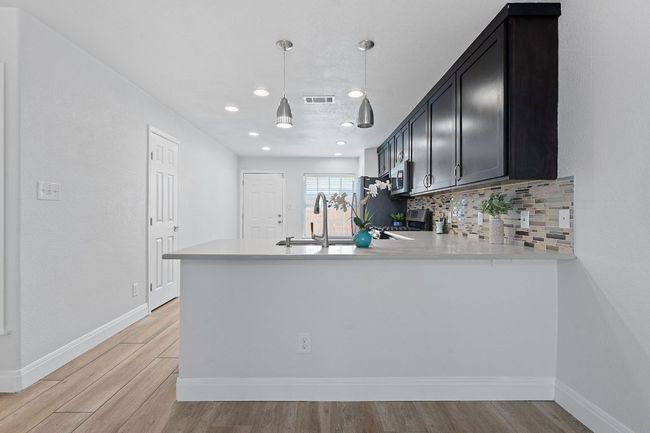 Kitchen featuring stainless steel appliances, a peninsula, light countertops, light wood-style floors, and recessed lighting | Image 7