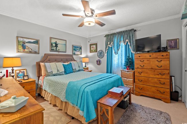 Bedroom featuring crown molding, light colored carpet, ceiling fan, and a textured ceiling | Image 17