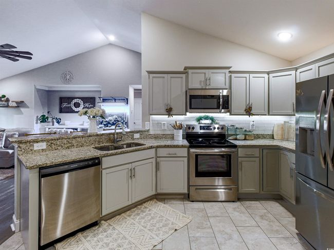 Kitchen with appliances with stainless steel finishes, sink, kitchen peninsula, backsplash, and vaulted ceiling | Image 12