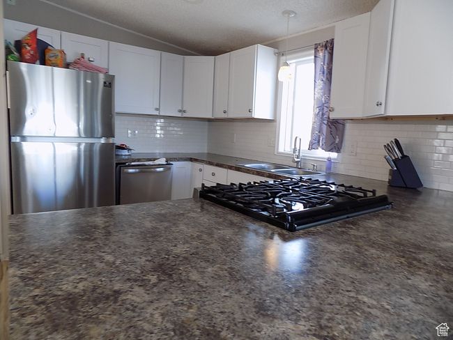 Kitchen with lofted ceiling, sink, appliances with stainless steel finishes, white cabinets, and backsplash | Image 6