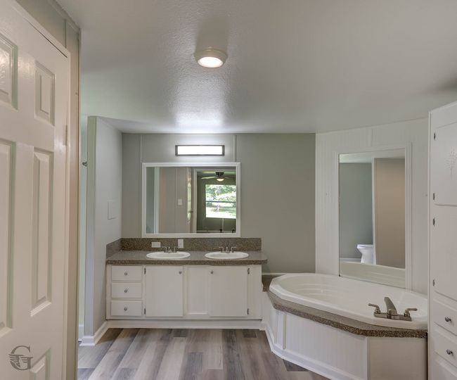 Full bath with a garden tub, double vanity, a textured ceiling, and wood finished floors | Image 10