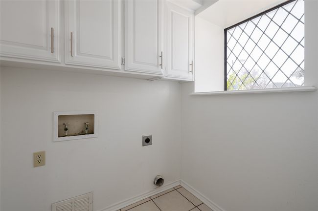 Washroom with light tile patterned floors, hookup for an electric dryer, washer hookup, visible vents, and cabinet space | Image 25