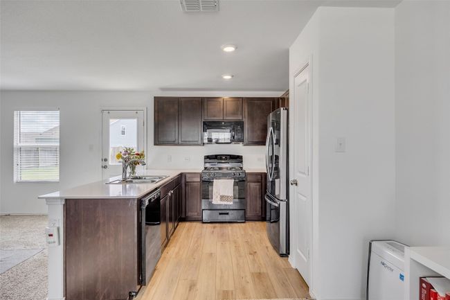 Kitchen featuring black appliances, a peninsula, dark brown cabinets, light countertops, and recessed lighting | Image 17