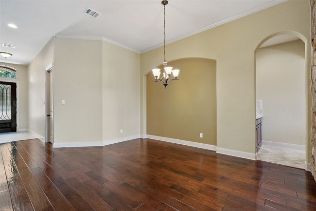 Spare room featuring a chandelier, wood finished floors, arched walkways, and crown molding | Image 11
