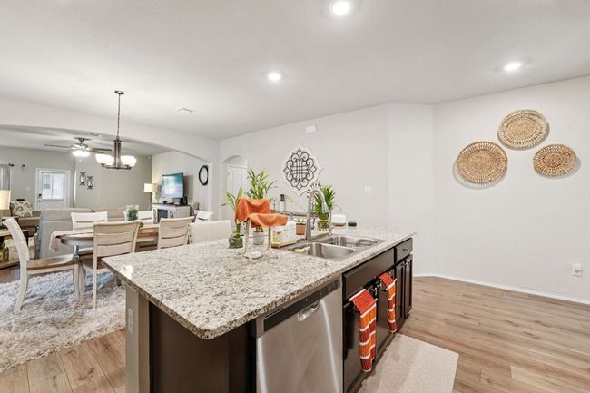 Kitchen featuring dishwasher, arched walkways, open floor plan, light wood finished floors, and a ceiling fan | Image 25
