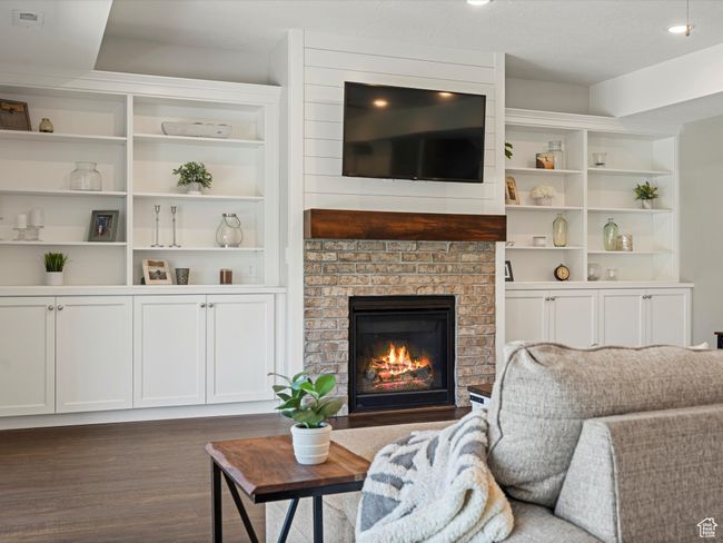 Living room featuring dark wood-style flooring, a fireplace, and built in shelves | Image 6
