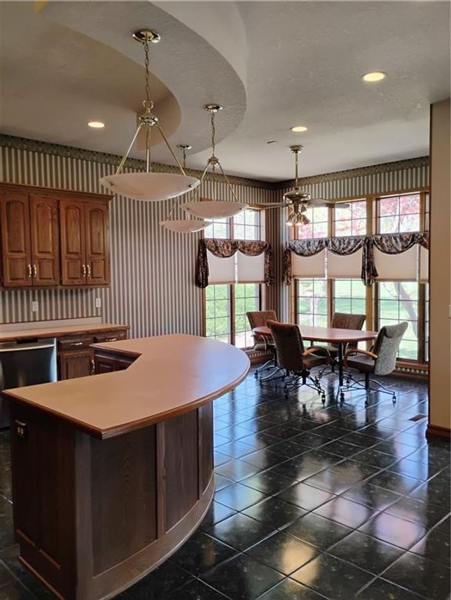 Kitchen featuring a center island, dishwashing machine, custom oak cabinetry, light countertops, and decorative light fixtures | Image 29