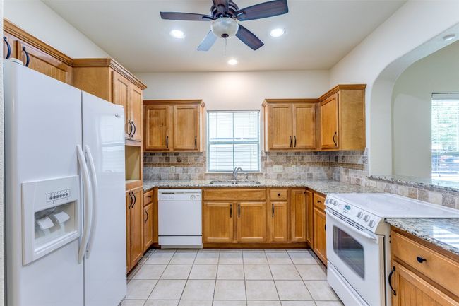 Kitchen with white appliances, healthy amount of natural light, backsplash, light tile patterned floors, and recessed lighting | Image 13