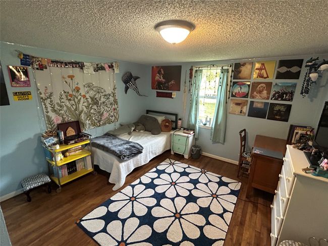 Bedroom with wood finished floors and a textured ceiling | Image 23