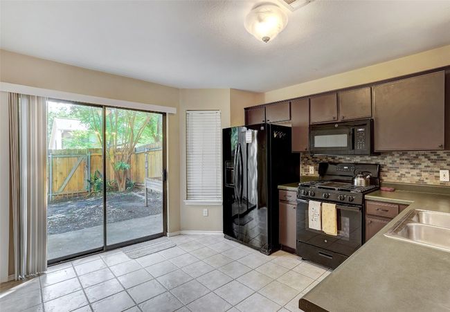 Kitchen featuring black appliances, a sink, backsplash, and baseboards | Image 17