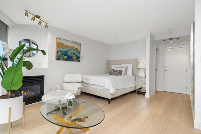 Interior space featuring rail lighting, a glass covered fireplace, plenty of natural light, and light wood-style flooring | Image 15