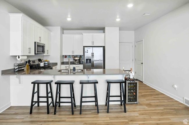 Kitchen with stainless steel appliances, a peninsula, new light wood-style LVP floors, a breakfast bar, and recessed lighting | Image 8