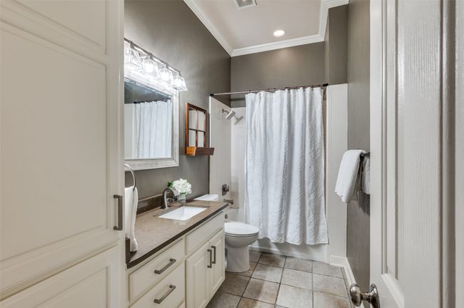 Full bath featuring tile patterned floors, crown molding, toilet, vanity, and shower / tub combo with curtain | Image 25