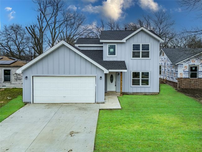 Modern farmhouse with a front lawn, concrete driveway, board and batten siding, and roof with shingles | Image 21