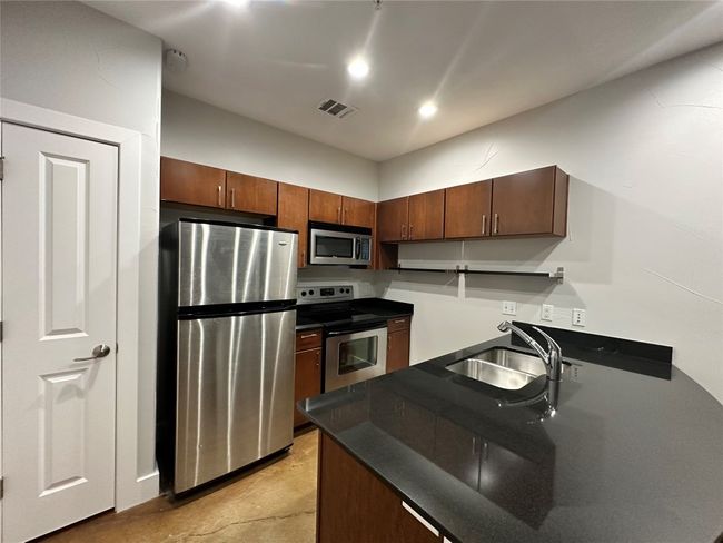 Kitchen with dark countertops, appliances with stainless steel finishes, and recessed lighting | Image 14