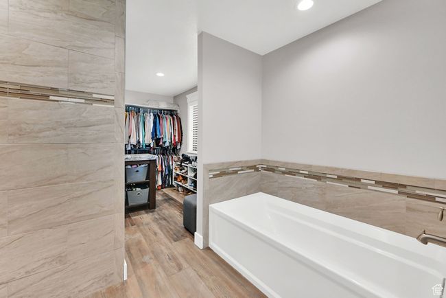 Bathroom with a bathtub, wood-type flooring, and tile walls | Image 22