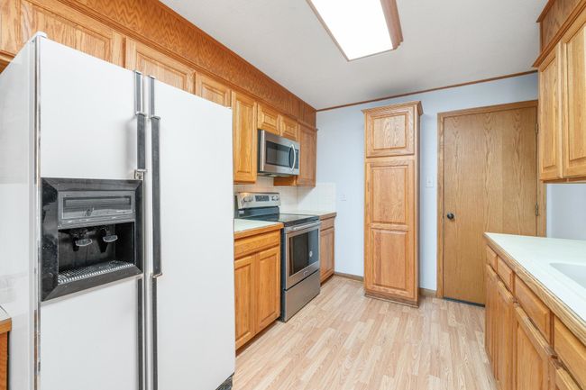 Kitchen featuring stainless steel appliances, light countertops, light wood-style flooring, tasteful backsplash, and crown molding | Image 17
