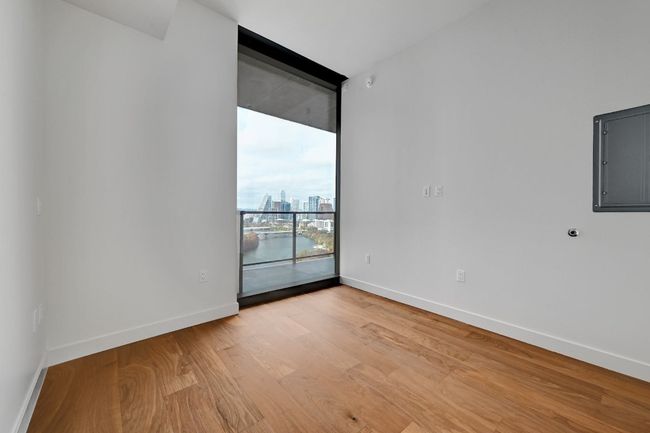 Empty room featuring light wood finished floors, electric panel, baseboards, and floor to ceiling windows | Image 9
