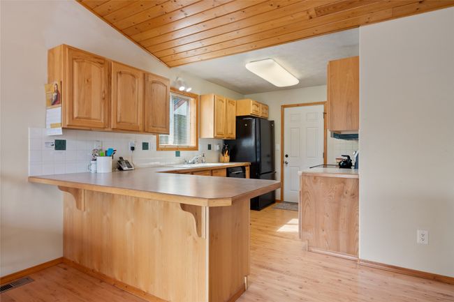 Kitchen with a kitchen bar, a peninsula, light wood-type flooring, and tasteful backsplash | Image 26