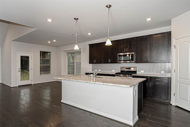 Kitchen featuring dark wood finished floors, a sink, backsplash, and appliances with stainless steel finishes | Image 10