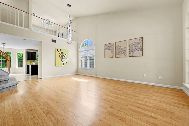 Unfurnished living room featuring light wood-type flooring, healthy amount of natural light, stairway, and a high ceiling | Image 7
