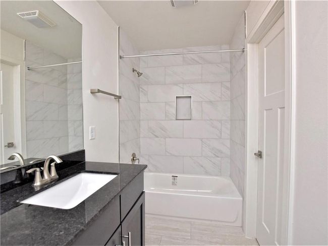 Bathroom featuring vanity, bathtub / shower combination, and marble look tile flooring | Image 19