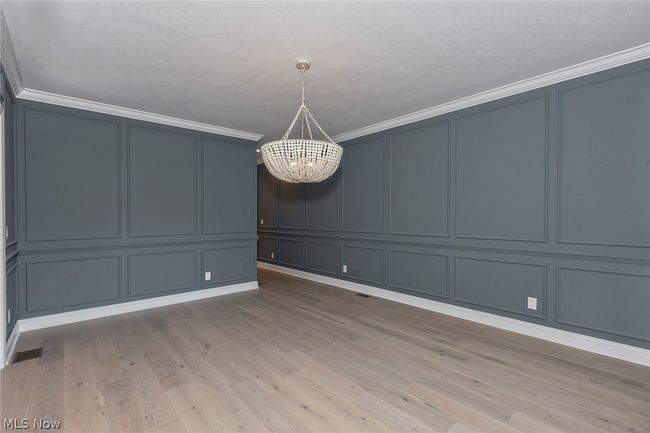 Empty room with a notable chandelier, hardwood / wood-style floors, and crown molding | Image 7
