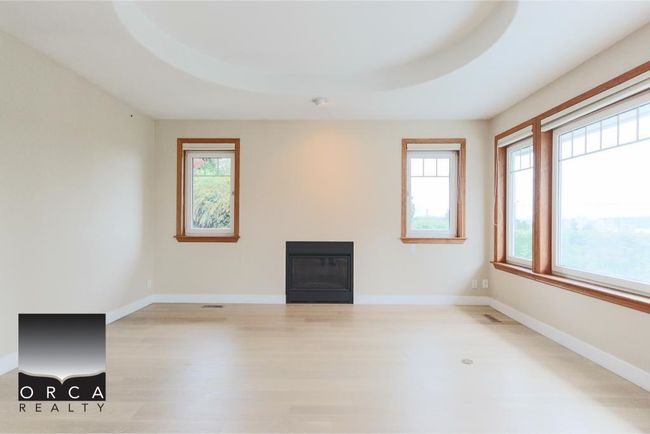 Empty room with plenty of natural light, wood finished floors, and a glass covered fireplace | Image 8