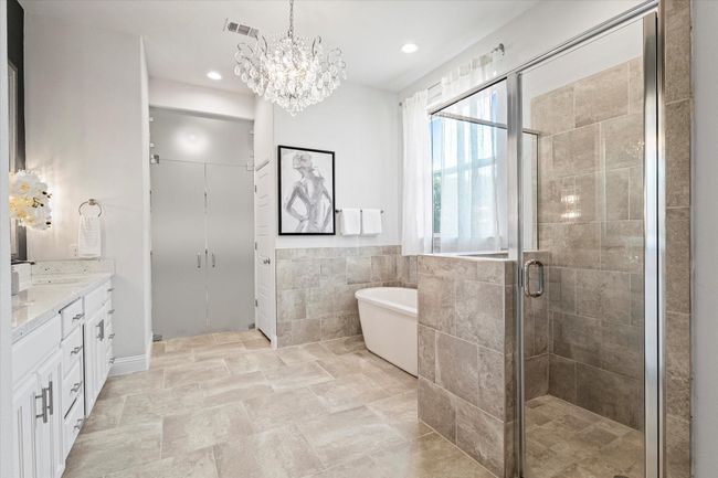 Full bath featuring vanity, a freestanding tub, a shower stall, tile walls, and a chandelier | Image 19