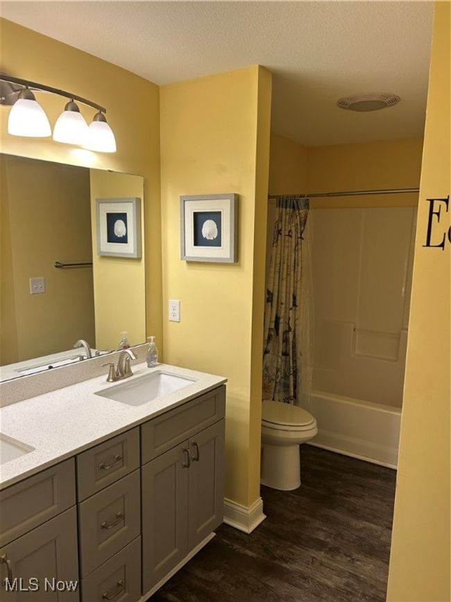 Bathroom featuring a textured ceiling, a sink, toilet, and wood finished floors | Image 7