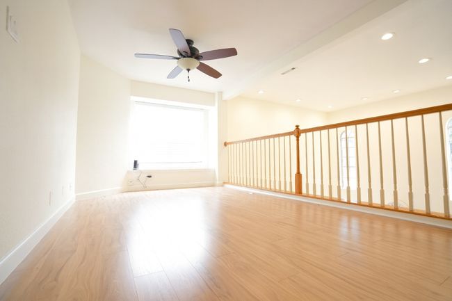 Empty room with beam ceiling, light wood-style floors, ceiling fan, and recessed lighting | Image 10