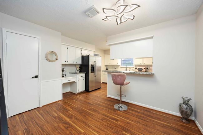 Bright, well-maintained kitchen featuring a breakfast bar and ample cabinetry and shelving for storage and organization. | Image 13