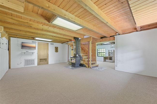 Lower Floor Living/Recreation Room. View of Small head Hi doors for storage to the left, Mechanical Room in the middle that is plumbed for a bath, Free Standing Wood Burning Stove, and Office Space, with walkout to Photographers back. | Image 18