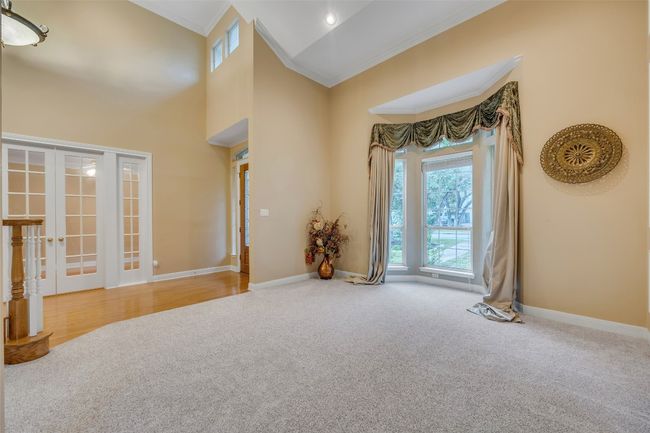 Carpeted spare room with ornamental molding, french doors, and a high ceiling | Image 10