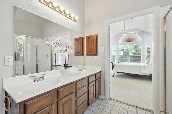 Full bathroom featuring tile patterned flooring, double vanity, ensuite bath, a shower stall, and lofted ceiling | Image 22