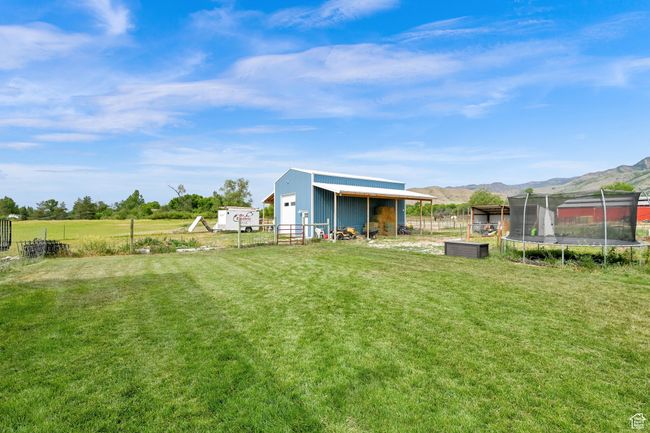 View of yard featuring a trampoline, an outdoor structure, a pole building, and a mountain view | Image 59