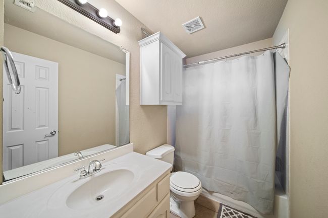 Full bathroom with a textured ceiling, visible vents, toilet, tile patterned floors, and vanity | Image 29
