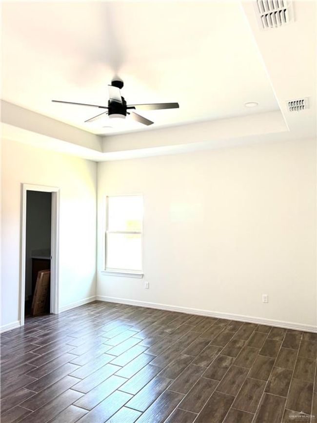 Unfurnished room with a ceiling fan, dark wood-style flooring, a tray ceiling, and visible vents | Image 12